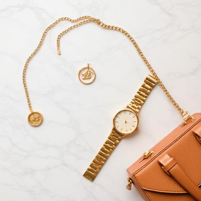 Flat lay: gold jewelry, watch, bag on a marble surface